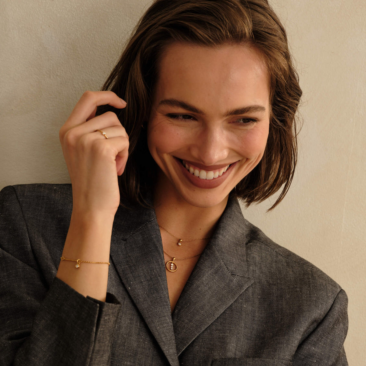 Smiling model wearing the MILLSÉ Eternal Grace 14k gold vermeil lab grown diamond jewelry set in an editorial portrait.