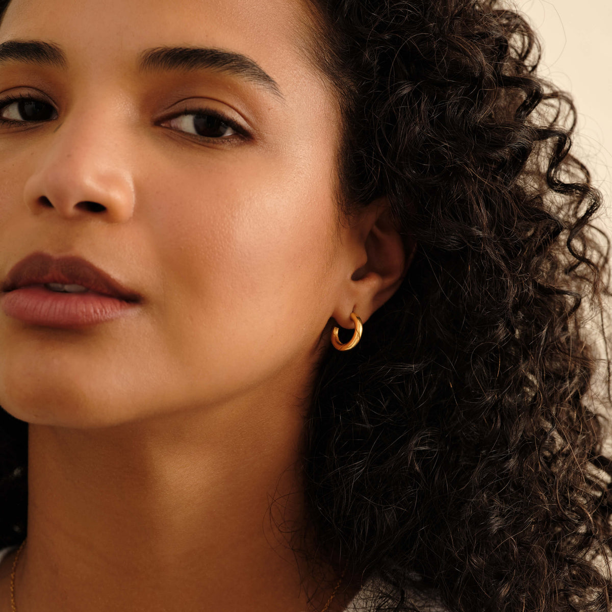 Model wearing the MILLSE Eternal Grace 15mm 14k gold vermeil hoop earrings in a close-up editorial portrait.