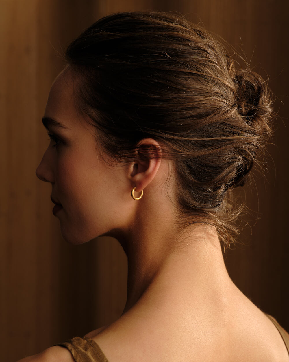 Woman wearing the Eternal Grace 15 mm 14k gold vermeil hoop earrings by MILLSÉ featuring the signature twist design. 